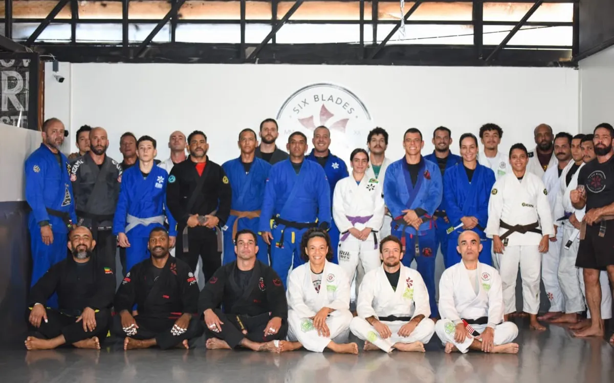 Professores e alunos da Six Blades Sudoeste reunidos diante do brasão da academia